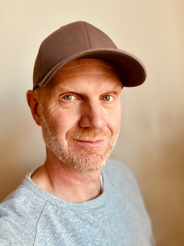 Mathias Clarstedt i keps och grå tröja, framför en ljus vägg